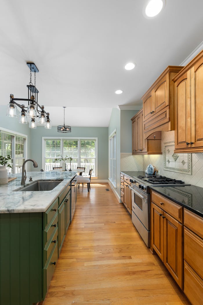 Spacious modern kitchen with wooden cabinets and marble countertops, featuring natural light and cozy dining area.