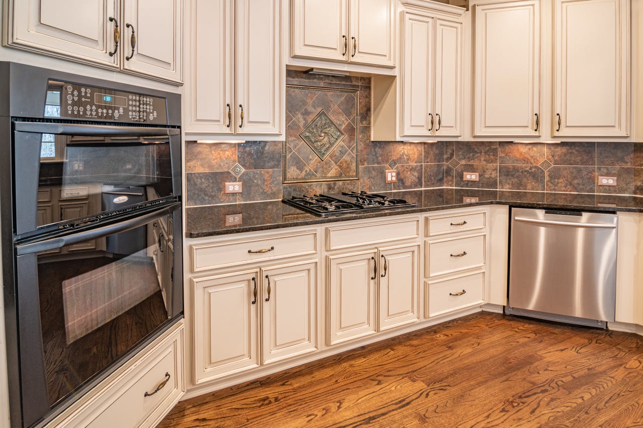 A modern kitchen featuring cabinets, a dishwasher, and a double oven with hardwood floors.